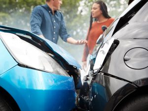 Two people conversing at the scene of a front to back car accident.